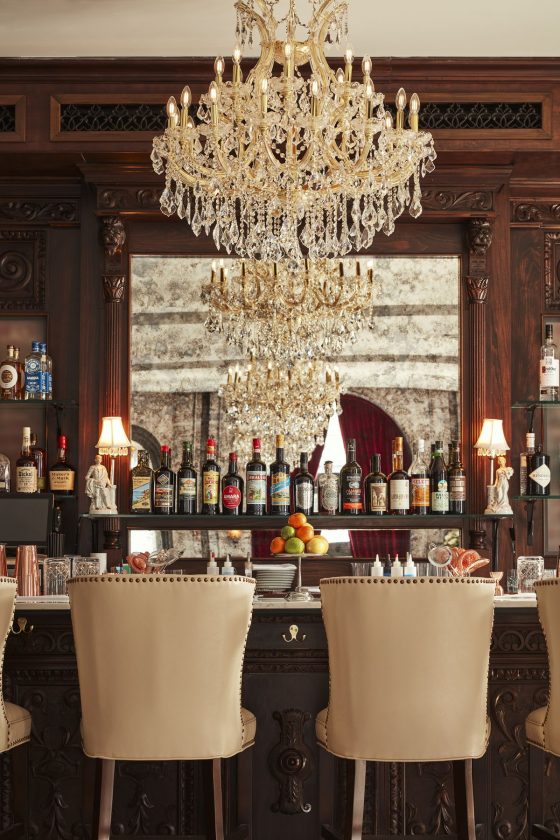 bar with chandelier and seats and mirror behind the bottles